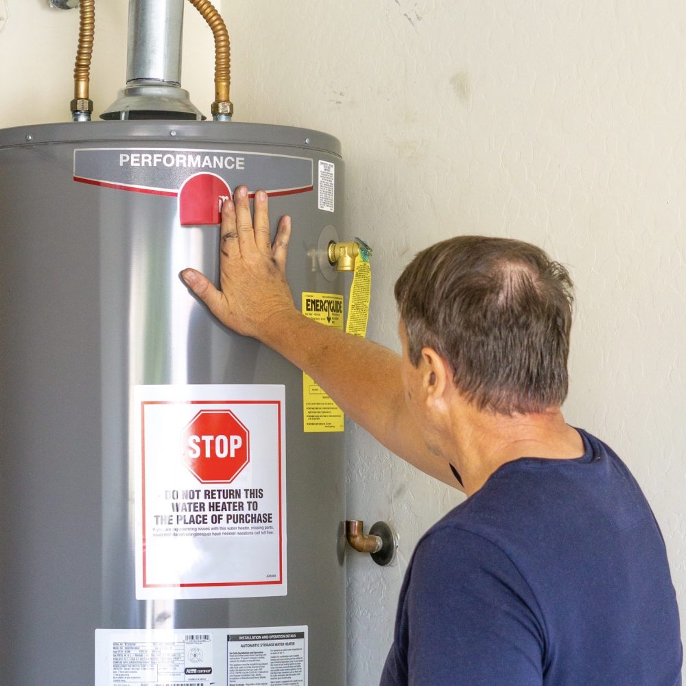 Adult male with hand on newly installed hot water heater