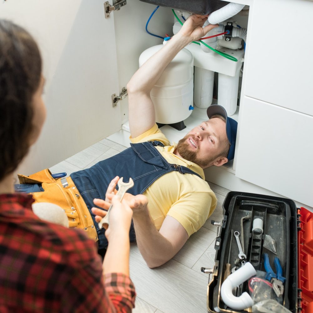 Handsome plumber fixing sink pipe